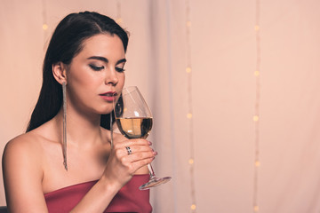 beautiful, dreamy girl holding glass of white wine in restaurant