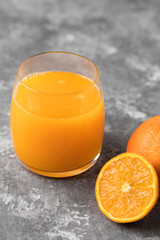 A close-up of a squeezed orange juice in a clear glass on a gray background