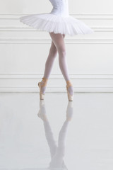 Young ballerina legs on pointe in light ballroom (Focus is on the skirt) - obrazy, fototapety, plakaty