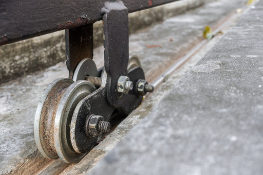 Dirty rusty steel roller wheels of sliding gates on concrete floor.