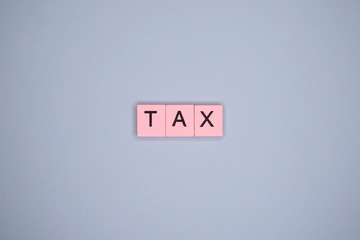 Tax word wooden cubes on blue background