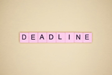 Deadline word wooden cubes on yellow background.