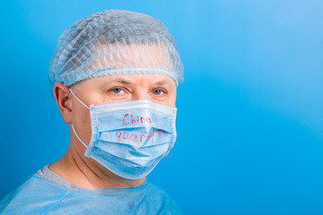 Portrait of man wearing medical uniform and mask with China quarantine word at blue background. Protect your health. Coronavirus concept with copy space