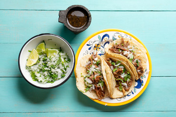 Mexican slow cooked lamb tacos also called barbacoa on turquoise background © Guajillo studio