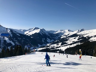 Beautiful ski panorama: Ski slope with ski lifts (chairlifts) and unidentifiable skiers in front of mountain panorama in Saalbach-Hinterglemm, Austria.