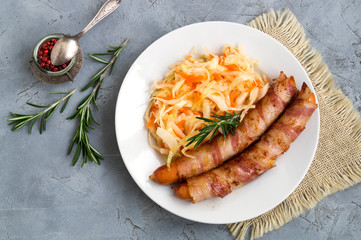 fried sausages with bacon on a plate.