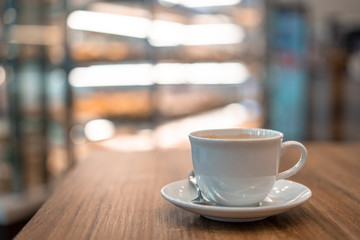 	
The white ceramic coffee cup with coaster is placed on a brown wooden base on the back, naturally a blurred background.