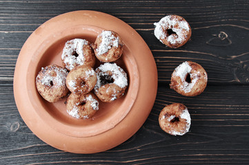 curd rings with topping from powder in a plate on a wooden background