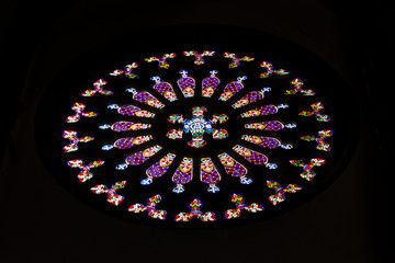Circular shape stained glass window inside Arucas cathedral in Gran Canaria, Spain. Colorful mandala style decoration over black background. Catholic religion concept