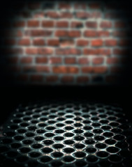 metal perforated table surface in a dark basement against a brick wall close up