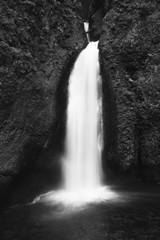 Closeup grayscale shot of a waterfall in a cliff and a lake - 322610526
