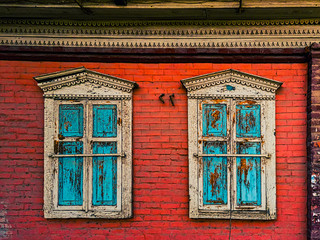 Closed wooden shutters on the windows in the red brick wall of the house