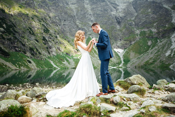 The bride and groom near the lake in the mountains. A couple together against the backdrop of a mountain landscape. Morskie Oko Lake. Tatra mountains in Poland. © ostap_davydiak