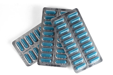 Blue medical capsules in blisters isolated on a white background.