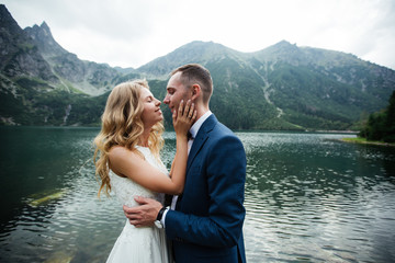 The bride and groom near the lake in the mountains. A couple together against the backdrop of a mountain landscape. Morskie Oko Lake. Tatra mountains in Poland. © ostap_davydiak