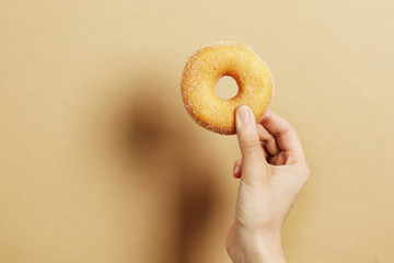 Woman holding delicious donut on color background