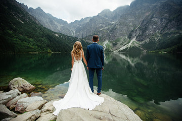 The bride and groom near the lake in the mountains. A couple together against the backdrop of a mountain landscape. Morskie Oko Lake. Tatra mountains in Poland. © ostap_davydiak
