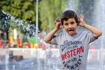 Niño feliz haciendo gesto con fuente de agua detrás