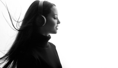 Fototapeta premium Beautiful woman in headphones listening music with closed eyes. Black and white. Free space for text.