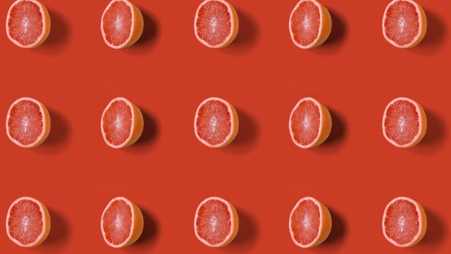 Stop motion minimal animation Top view on grapefruit halves rotating, wiggling or dancing on orange background. loopable. Real fruits. 4k.