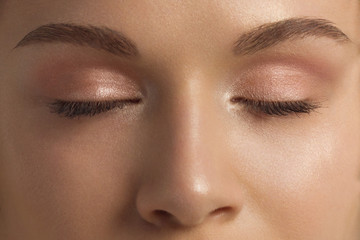 Macro shot of beautiful eyes of the girl with beautiful eyebrows and long eyelashes. One eyebrow is raised. Brown shades in a make-up. Cosmetology, Spa, correction, injections