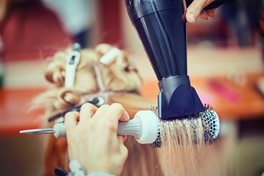 Hairdresser styling hair dryer in a beauty salon