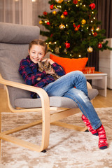 Little girl playing with cute kitty near christmas tree