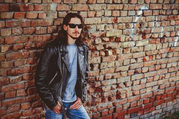 Fototapeta na wymiar a man in a leather jacket against a brick wall