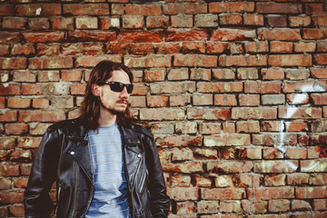 Fototapeta na wymiar a man in a leather jacket against a brick wall