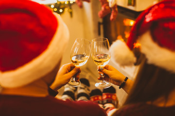 Back view Christmas couple near fireplace, toasting