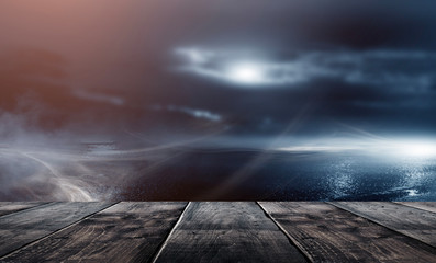 Night landscape and wooden table. Moonlight reflected on the water. Trees, dark street, wet asphalt.