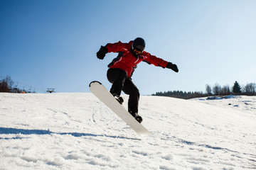 Male snowboarder in action jumping over hill