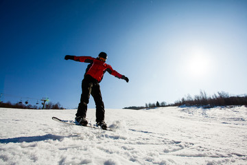 Fototapeta na wymiar Professional snowboarder riding down the snow slope