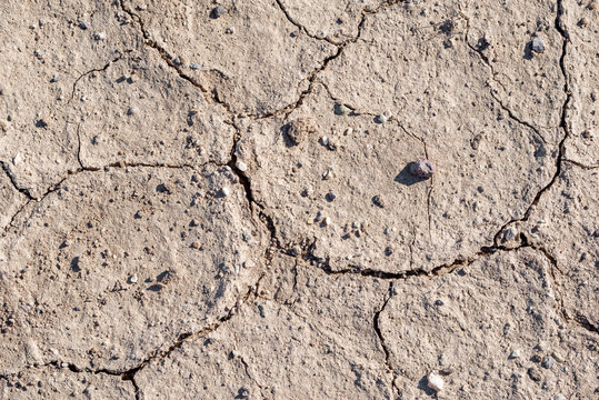 A natural background texture of cracked clay and gravel. Soil from the earth.