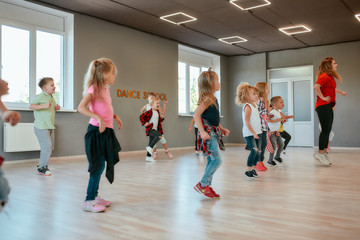 Repeat after me. Group of active children dancing in front of the large mirror while having...