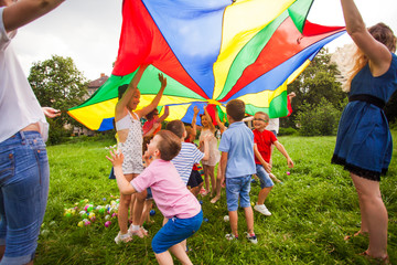 Kids hide under rainbow parachute outdoors game