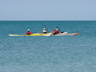 Group of kayakers paddling across a calm Gulf of Mexico at St. Pete Beach, Florida.