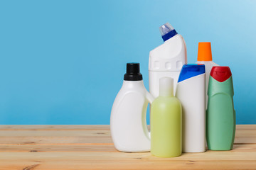 Cleaning product plastic container for house clean on wooden table and blue background . household chemicals
