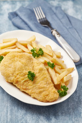 Pork Schnitzel with french fries on wooden background.