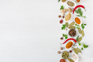Various assorted colorful spices and herbs on white wooden background top view.