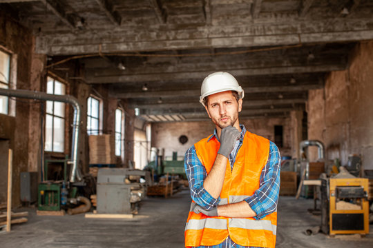 Man Standing At The Old Factory In A Protective Helmet