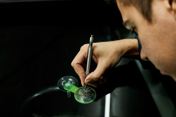 A mechanic uses repair equipment to repair a damaged windshield. It repairs glass chips with an injector under pressure and uses a special polymer.