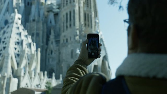 A man is taking picture of gothic church, Sagrada familia, Barcelona. Close up.