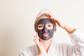 Beautiful young woman using a black face mask