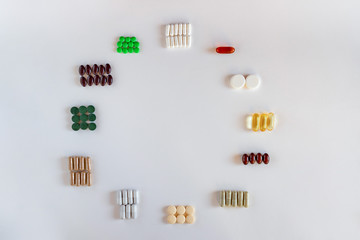 Medication with different types and colours as clock face on white background