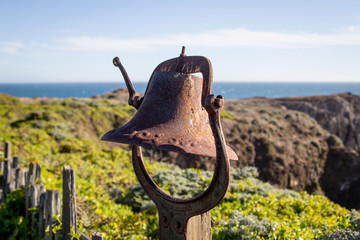 Fototapeta premium Rusty old brass bell by the sea coastline. 