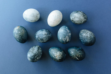 Beautiful group ombre blue Easter eggs with quail eggs and feathers on a blue background. Easter concept. Border eggs. Copy space for text