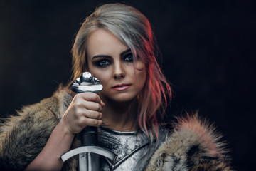 Portrait of a beautiful warrior woman holding a sword wearing steel cuirass and fur. Fantasy...