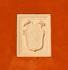 Old heraldic emblem with a damaged relief on a Venice red plaster wall