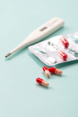 Antibiotic and thermometer. Highly blurred background photo.